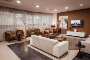 una sala de espera con un sofá blanco y sillas en Vitoria Hotel, en Fátima