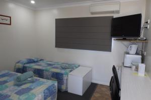a room with two beds and a flat screen tv at Three Moon Motel in Monto