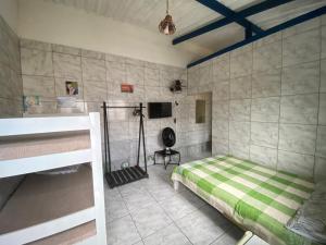 1 dormitorio con 1 cama y TV en la pared en Cantinho MurchioBom en Peruíbe