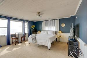 a bedroom with a large bed with blue walls and windows at Spacious Lakefront House with Backyard Fire Pit in Monroe