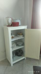 a white cabinet with plates and dishes on it at Red - Monolocale San Pantaleo in San Pantaleo