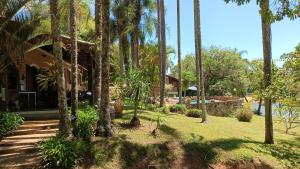 a house with palm trees in front of a yard at Casa de Campo em Ibiúna de frente para represa in Ibiúna