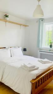 1 dormitorio con 1 cama blanca grande y ventana en Amazing Location - City of London- 2 Bedroom Stunning Canal View House With Private Garden,Parking & Balcony, en Londres