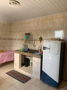 a kitchen with a counter and a white refrigerator at Pousada Korui in Abraão