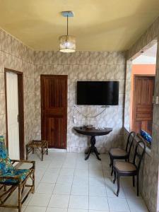 a living room with a table and chairs and a tv at Pousada Korui in Abraão