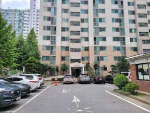 un aparcamiento con coches estacionados frente a un gran edificio en Yeongtong Family House en Suwon