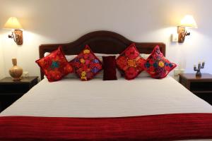 a bedroom with a bed with red pillows at Hotel Antiguo Fortin in Oaxaca City