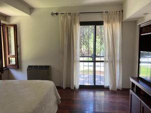 a bedroom with a bed and a large window at HABITACION CON PISCINA Y PARQUE en Chacras de Coria in Chacras de Coria