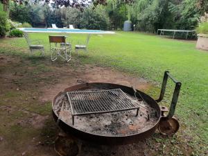 a grill in a yard with a table and chairs at HABITACION CON PISCINA Y PARQUE en Chacras de Coria in Chacras de Coria