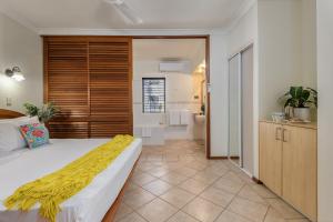 a bedroom with a bed with a yellow blanket on it at Poolside Villa - Hibiscus 40b in Port Douglas +3 photos
