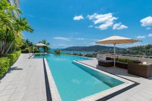 a swimming pool with an umbrella and a view of the ocean at Whitsunday Wonderview in Airlie Beach