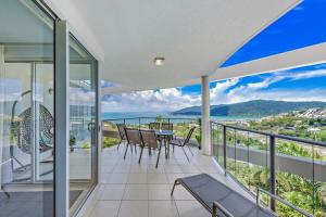 Casa vacía con balcón con mesa y sillas en Whitsunday Wonderview, en Airlie Beach