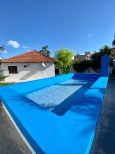 a blue swimming pool in front of a house at Termas de Río Hondo Casona Laconte in Termas de Río Hondo