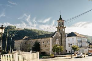 Una vieja iglesia de piedra con un campanario en una calle en APARTAMENTOS CASA ARADIÑA, en Ríotorto