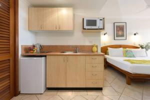a kitchen with a sink and a bed in a room at Poolside Villa - Hibiscus 40a in Port Douglas