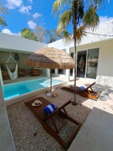 a patio with two chairs and an umbrella and a pool at Villa Kuxtah, Beautiful bungalow with Private Pool in Tulum