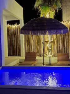 a swimming pool with an umbrella and two chairs at Villa Kuxtah, Beautiful bungalow with Private Pool in Tulum
