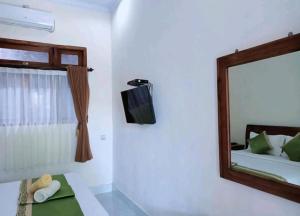 a mirror in a room with a bed and a tv at Green Palace Homestay in Nusa Penida