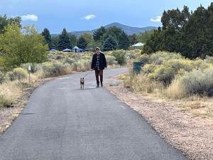 a woman walking a dog down a road at Santa Fe Charm Home in Santa Fe