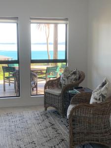 a living room with wicker chairs and a view of the ocean at Sea Veiws Kaha Place in Russell