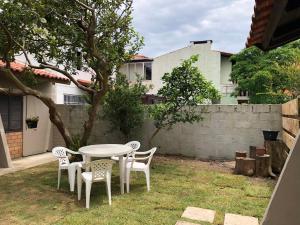 un tavolo bianco e sedie in un cortile di Casa a 100 mts da praia! a Garopaba