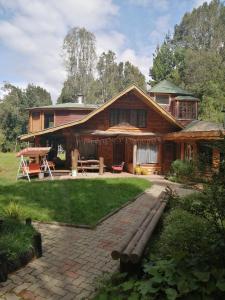a large wooden house with a patio in the yard at Valle el Abra Ralún Lodge in Puerto Varas