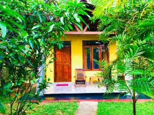 Casa amarilla con puerta de madera y silla en Sungreen Cottage Sigiriya en Sigiriya