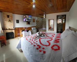 a bedroom with a bed with red flowers on it at Pousada Florada da Serra in Monte Verde