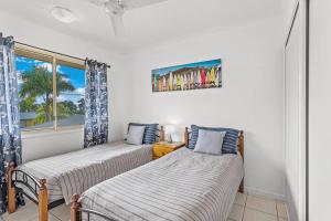 two beds in a room with a window at The Lazy Breeze in Cannonvale
