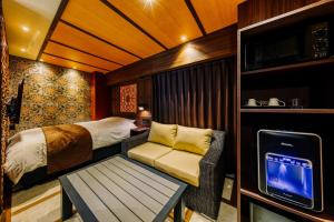 een slaapkamer met een bed, een bank en een tv bij Hotel Lotus Okayama Adult Only -Adult Only in Okayama