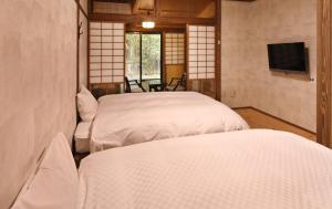 a room with two beds and a tv in a room at Yamashinobu in Minamioguni