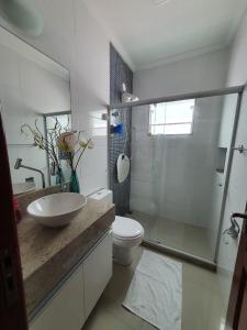La salle de bains est pourvue d'un lavabo, de toilettes et d'une douche. dans l'établissement Casa Azul - Linda casa Familiar com Piscina no Peró em Cabo Frio, à Cabo Frio