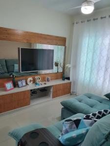 Il comprend un salon doté d'un canapé et d'une télévision à écran plat. dans l'établissement Casa Azul - Linda casa Familiar com Piscina no Peró em Cabo Frio, à Cabo Frio