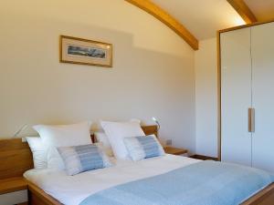 a bedroom with a bed with white sheets and blue pillows at High Trodigal in Machrihanish