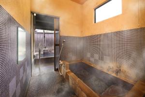 a bathroom with a large tub with a window at Yamashinobu in Minamioguni