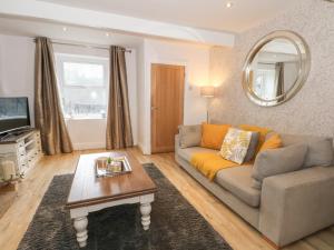 a living room with a couch and a mirror at Springwood Cottage in Holmfirth