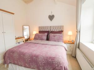 a bedroom with a bed with a purple bedspread at Springwood Cottage in Holmfirth