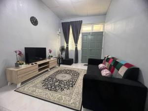 a living room with a couch and a tv at 2 Bedroom house with Coway, all room air-cond, WIFI, Nettflix in Kampung Gurun