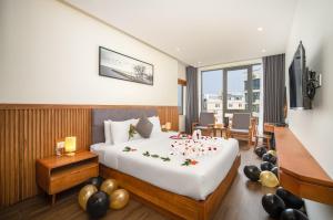 a bedroom with a large white bed with candles on it at Yes Hotel Đà Nẵng in Danang