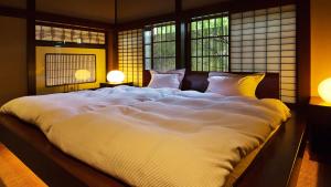 a large white bed in a room with windows at Kocho in Kaga