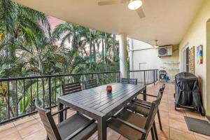 een tafel en stoelen op een balkon met palmbomen bij ZEN FORESHORE Cozy 2-BR, 2-BA Holiday Home + Pool in Nightcliff