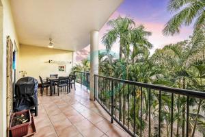 a balcony with a table and chairs and palm trees at ZEN FORESHORE Cozy 2-BR, 2-BA Holiday Home + Pool in Nightcliff