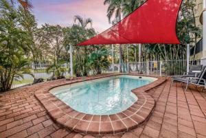 una piscina con una sombrilla roja. en ZEN FORESHORE Cozy 2-BR, 2-BA Holiday Home + Pool, en Nightcliff
