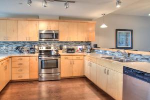 uma cozinha com armários de madeira e electrodomésticos de aço inoxidável em Feelin Beachy Condominium em Ocean Shores