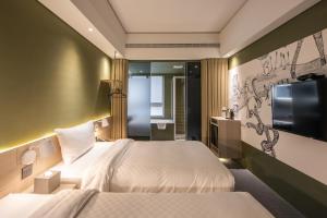 a hotel room with two beds and a flat screen tv at Ramble Hotel in Taichung