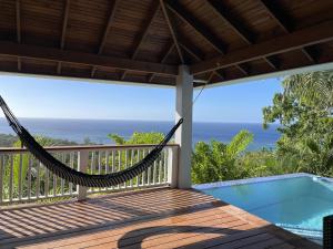 a hammock on a porch with a view of the ocean at Top Ridge Views - 2 Bedrooms in Sandy Bay