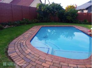 a brick pathway around a swimming pool in a yard at 4 on Verbena in Boksburg