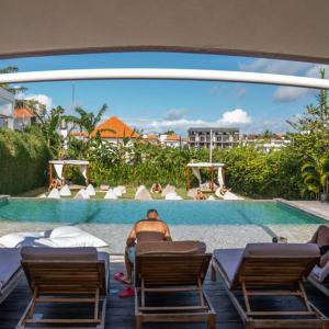 a man sitting in a chair next to a swimming pool at Body Factory Bali in Canggu