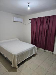 1 dormitorio con cama y cortina púrpura en Departamento con excelente ubicación en Yerba Buena