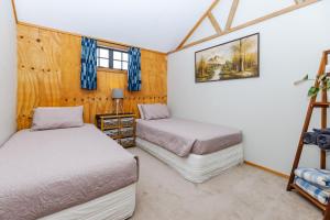 two beds in a room with wooden walls at Nadarra Hideaway in Otorohanga
